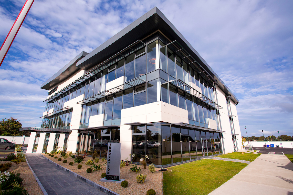 Exterior view of glass clad building that is M11 Business Campus in Gorey, Co. Wexford. It is a multi-storey, modern looking square building with fresh landscaping.