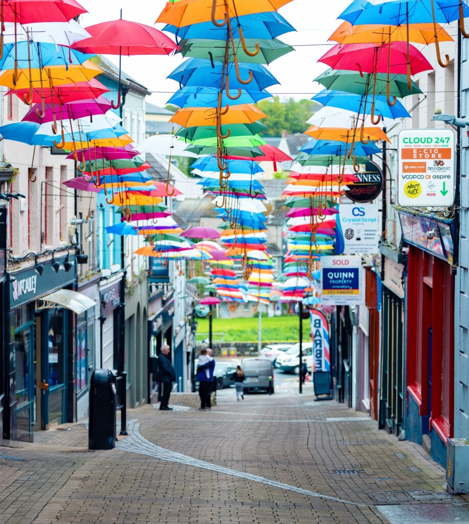 A street with multicoloured umbrellas hanging above to decorate the area