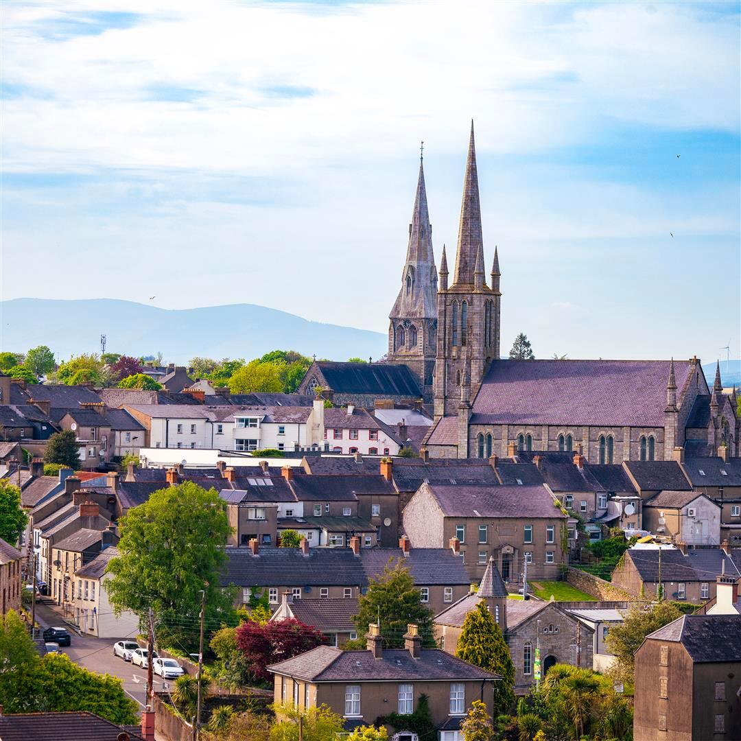 A drone view of Enniscorthy town with buildings in the foreground and the spire of St. Aidan's Cathedral in the background