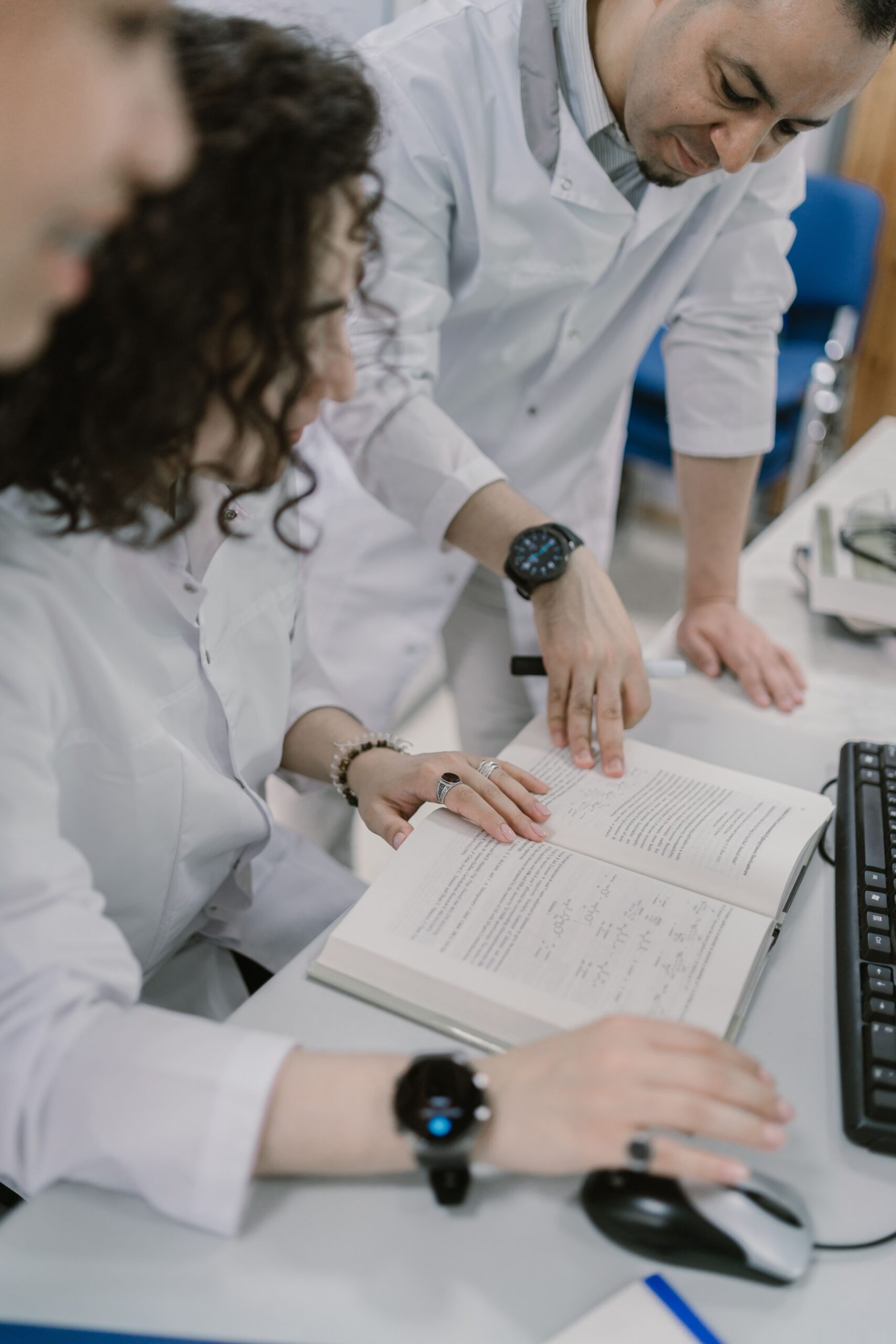 Scientists in lab coats reading a book and discussing chemical experiments in a modern lab