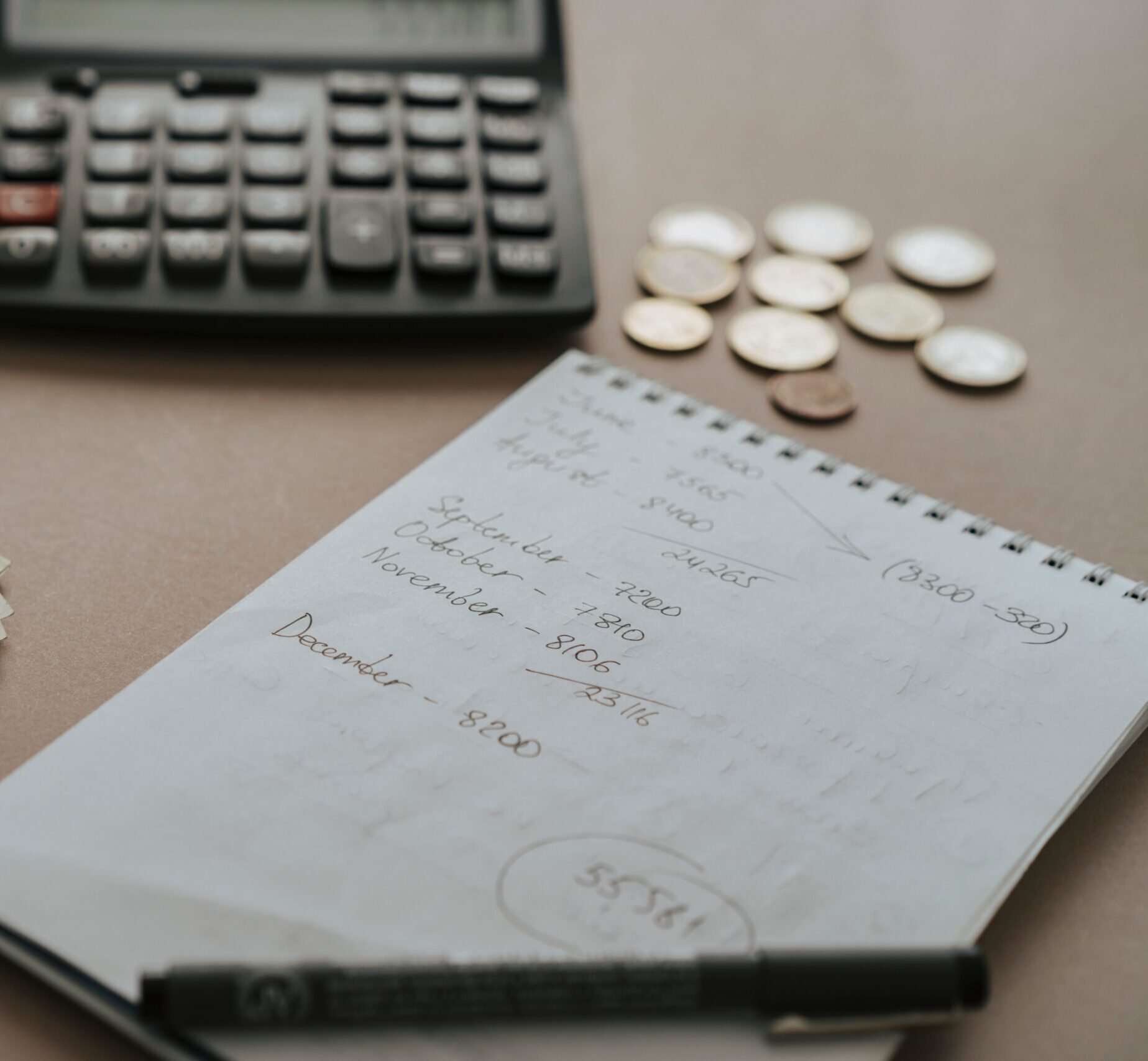 Desk setup showing calculator, cash, coins, and financial notes for budgeting.