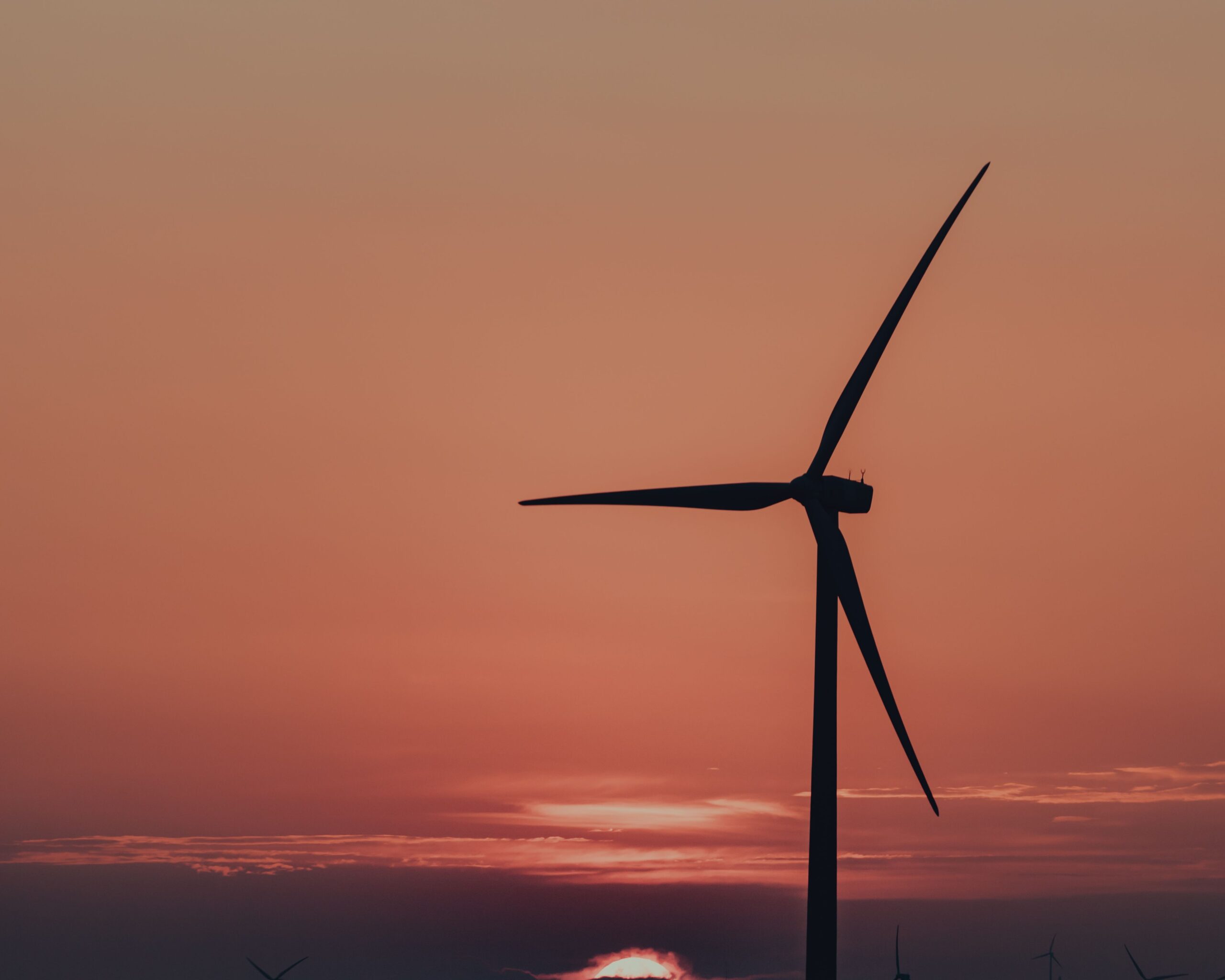 A red sunset gradient sky and to the right of the photo is the silhouette of a wind turbine