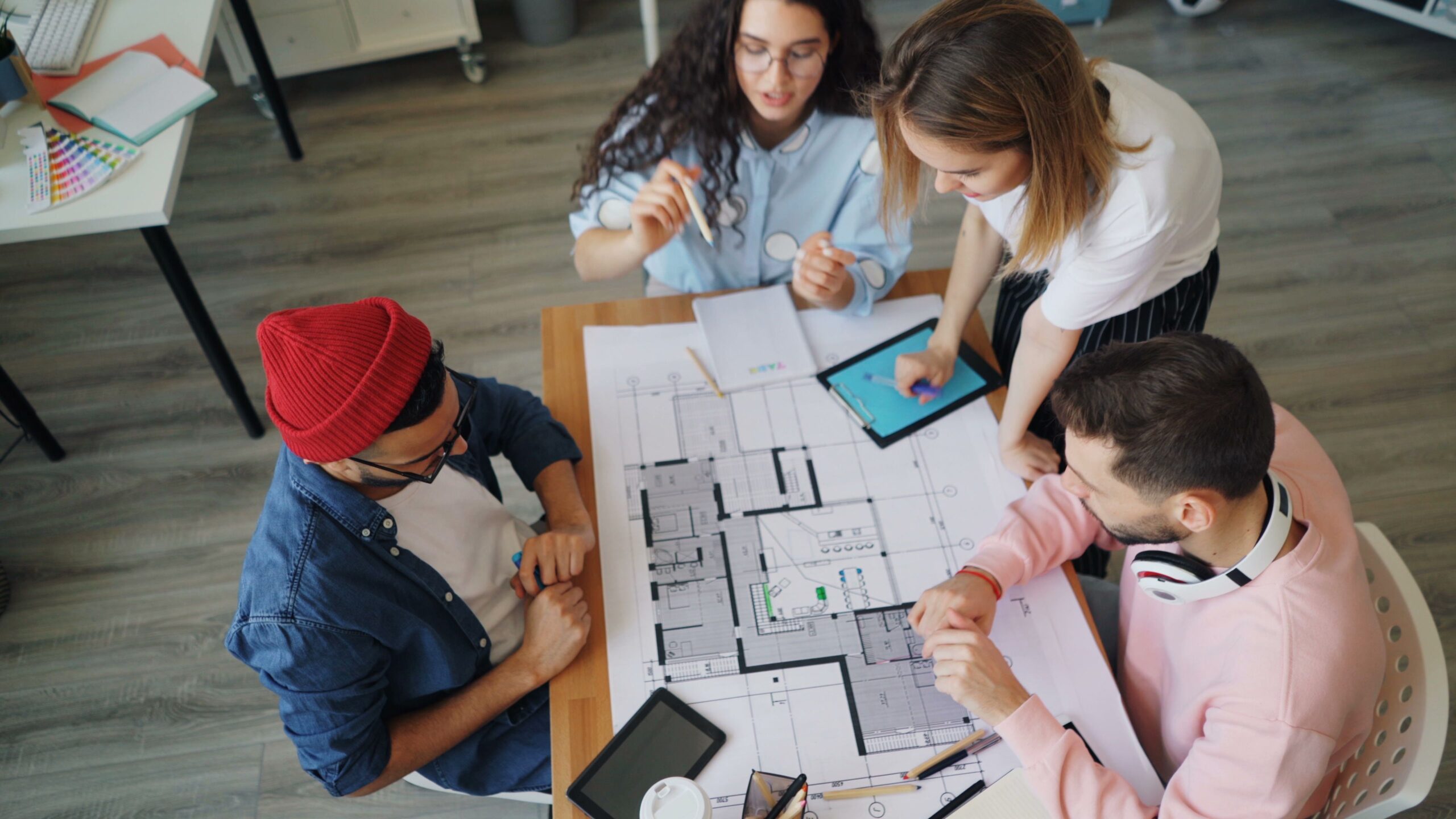 4 people sitting around a table looking at a blueprint of a building