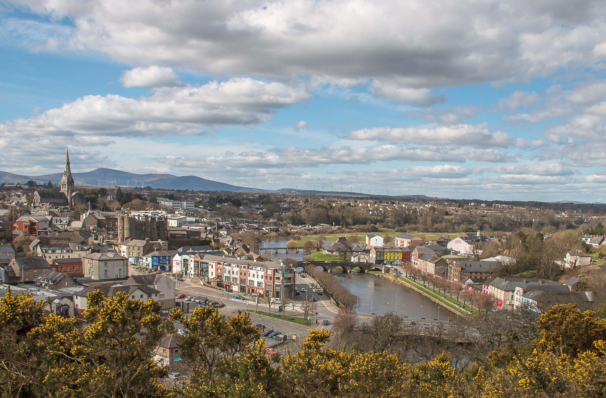 An image of Enniscorthy Town from a height with the River Slaney flowing through the town to the right of the image, a spire of the cathedral to the left of the image and the Blackstairs mountains in the background