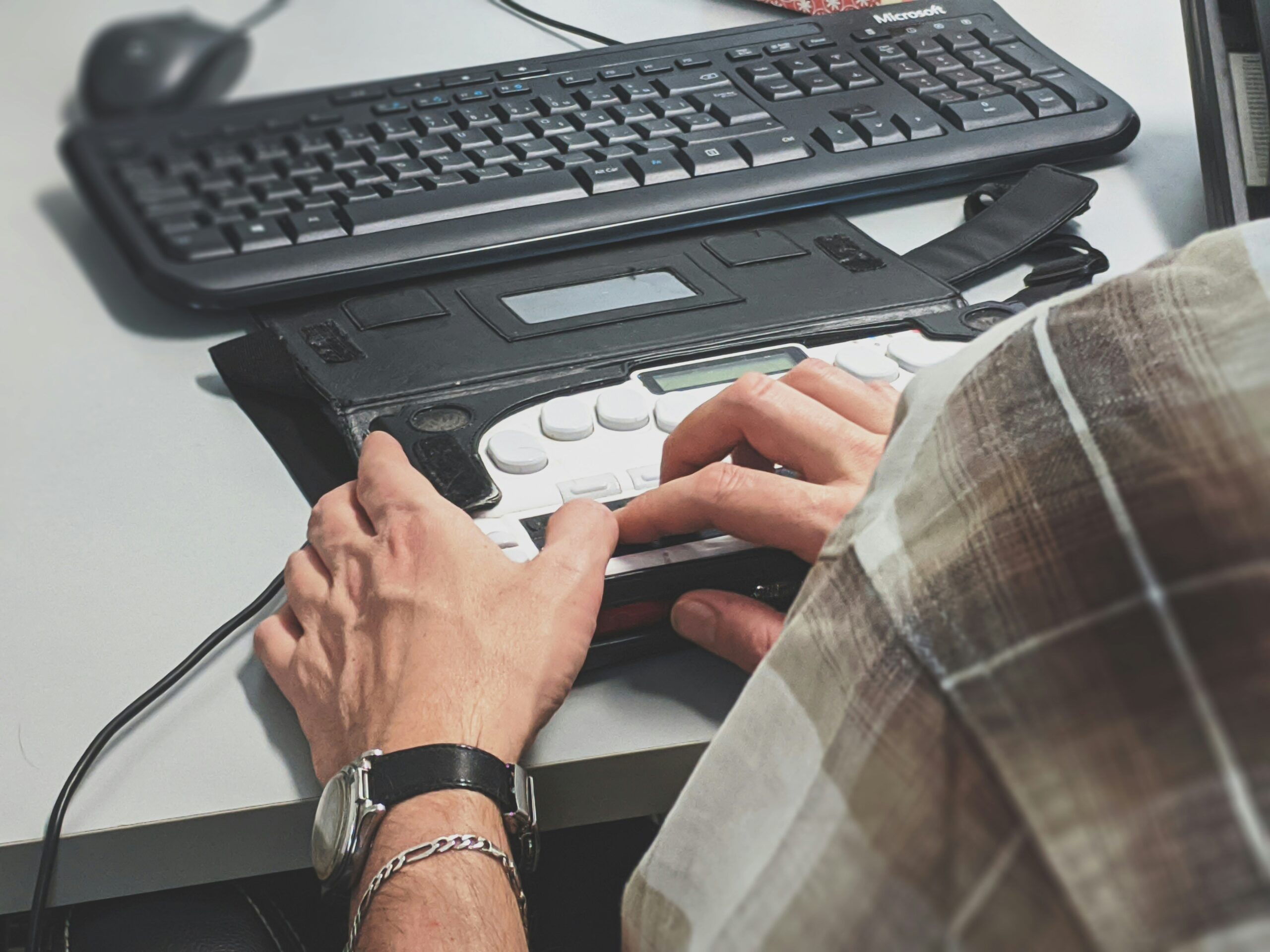 Person using a braille keyboard attachment for computer