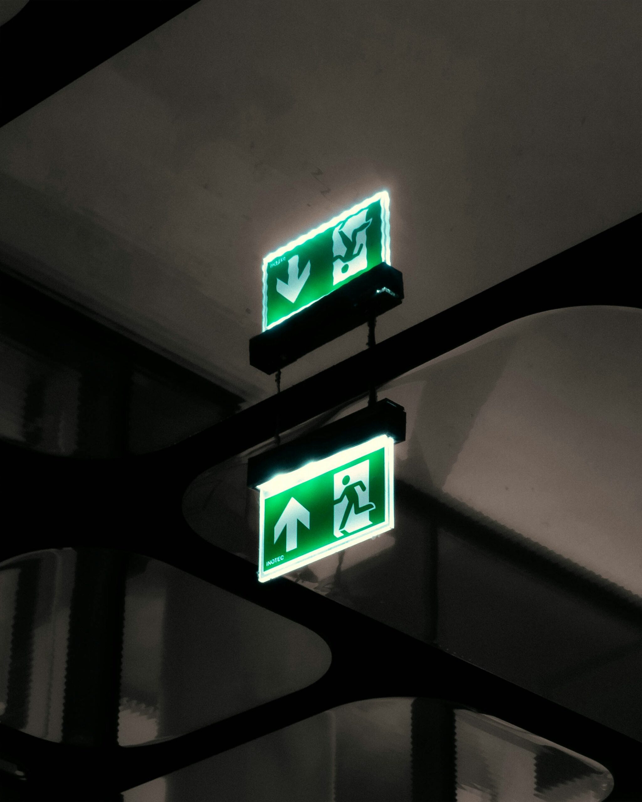 Bright green emergency exit sign illuminated and hanging from the ceiling
